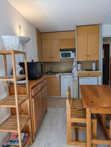 une cuisine avec des armoires en bois et une table en bois dans l'établissement STUDIO CABINE aux BALCONS DU SOLEIL, à Font-Romeu