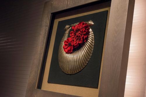 a picture of a vase with a red flower in it at ホテルディオールセブン郡山 in Koriyama