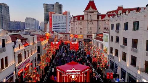 a large crowd of people walking down a city street at Hua Qi Kaiserdom Hotel Zhongshan Road St Michael's Cathedral and Zhanqiao Pier Qingdao in Qingdao