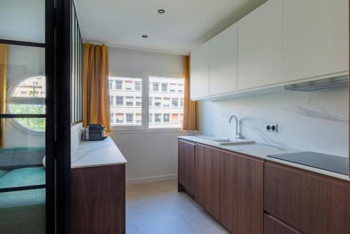 d'une cuisine avec des placards blancs, une fenêtre et un évier. dans l'établissement Paris La Defense Design residence, à Courbevoie