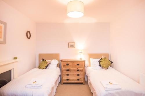 a bedroom with two beds and a dresser in it at Springkell in Eaglesfield