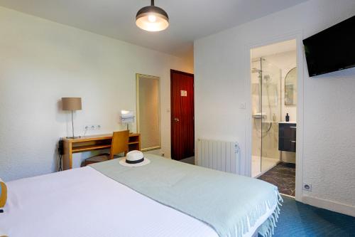 a bedroom with a large white bed and a desk at Hotel Le Branhoc - Brit Hotel Auray in Auray