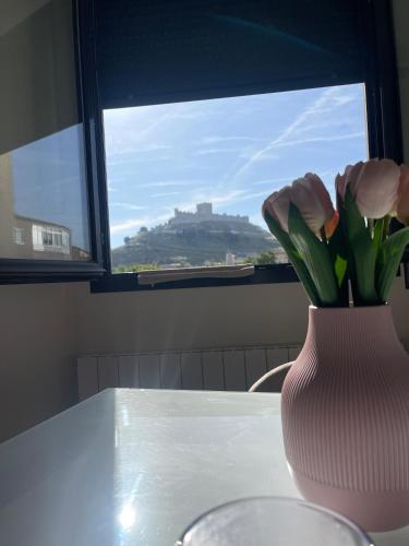 a vase of flowers sitting on a table with a window at Casa de la luz in Peñafiel