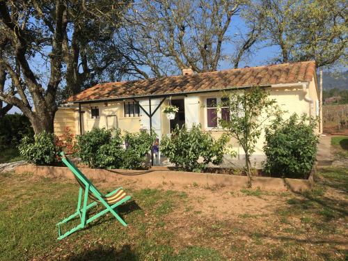 Une petite maison blanche avec un râteau vert dans la cour dans l'établissement La maison sous les chenes, à Vidauban