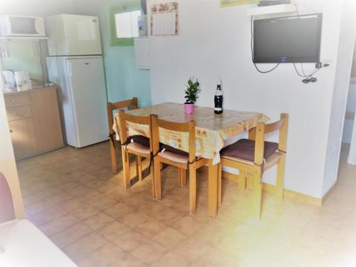 - une cuisine avec une table et des chaises ainsi qu'une bouteille de vin dans l'établissement La maison sous les chenes, à Vidauban