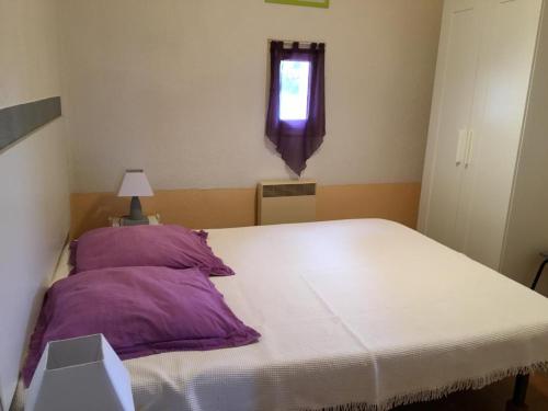 - une chambre avec un lit doté d'oreillers violets et d'une fenêtre dans l'établissement La maison sous les chenes, à Vidauban
