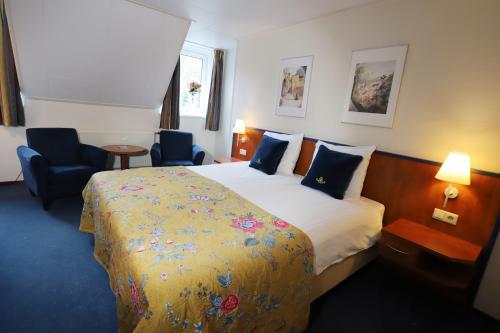 a hotel room with a bed and two chairs at Het Ros van Twente in De Lutte