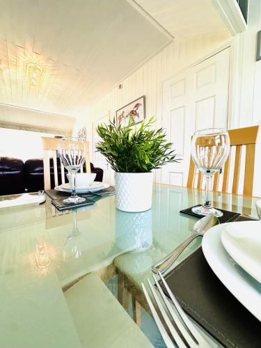 a dining table with glasses and a potted plant on it at Warren Cottage in Bridlington
