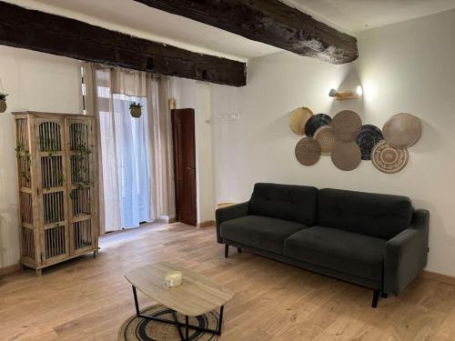 un salon avec un canapé noir et une table dans l'établissement Appartement T2 Cosy centre-ville, à Pernes-les-Fontaines