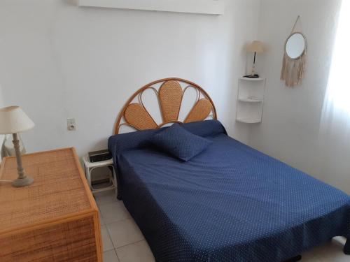une chambre avec un lit bleu et une table en bois dans l'établissement Maisonnette de plain pied, au Barcarès