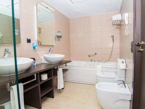a bathroom with two sinks and a tub and a toilet at Hotel RH Vinarós Aura in Vinaròs