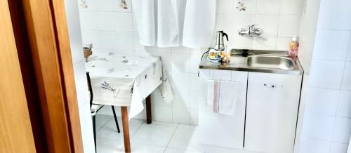 a small white kitchen with a sink and a table at La casa di mammona in Semivicoli