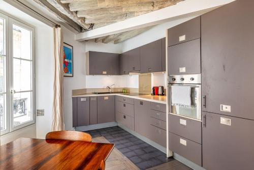 une cuisine avec des placards gris et une table en bois dans l'établissement GuestReady - Séjour confortable dans le 9ème, à Paris