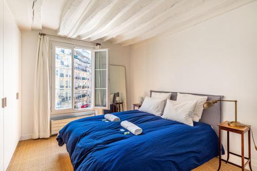 une chambre avec un lit avec des draps bleus et une fenêtre dans l'établissement GuestReady - Séjour confortable dans le 9ème, à Paris