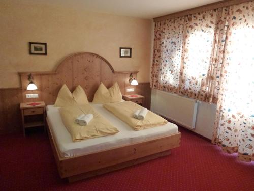 a bedroom with a large bed with yellow pillows at Hotel Garni Landhaus Trenkenbach in Schladming
