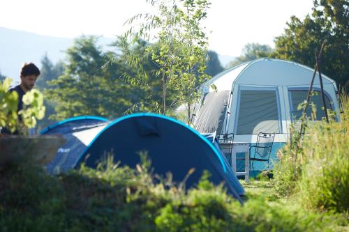a man standing next to two tents in a field at Camping Baleia in Pui