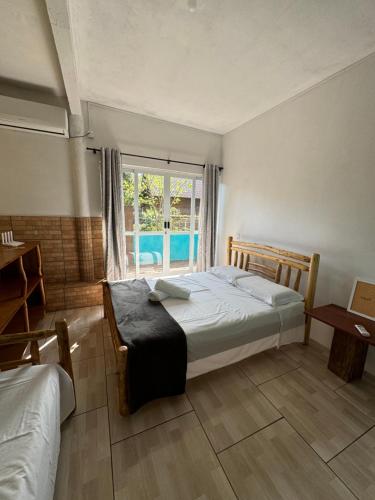 a bedroom with a bed and a window at Morada das Orquídeas in Guarda do Embaú