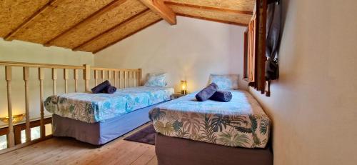 deux lits dans une chambre avec plafonds en bois dans l'établissement Escapades en Ventoux, à Venasque