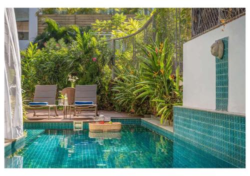 a swimming pool with two chairs and a table next to it at La Maroma 3 BHK Splendid Villas in Anjuna - Pvt Pool- Garden & Caretaker in Vagator