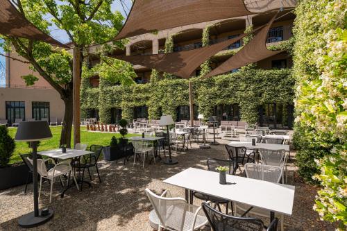 an outdoor patio with tables and chairs in front of a building at Hotel du Roi & Spa by SOWELL COLLECTION in Carcassonne