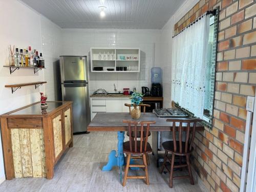a kitchen with a table and a refrigerator at Morada das Orquídeas in Guarda do Embaú