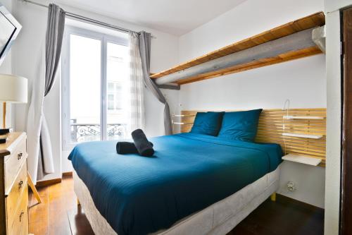 - une chambre avec un lit bleu et une grande fenêtre dans l'établissement Appartement Quartier Saint Marcel Free Netflix, à Paris