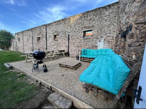 a room with a couch and a grill next to a brick wall at "L'escargot" Maison familiale - Les Terres du Roy in Avallon