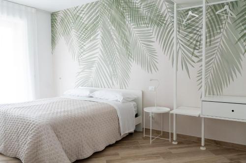 1 dormitorio con 1 cama y un mural de palmeras en Relais del Parco Verde e Relais del Parco Rosso, en LʼAquila