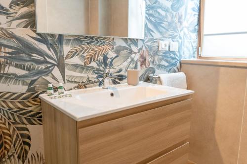 baño con lavabo blanco y papel pintado tropical en Relais del Parco Verde e Relais del Parco Rosso, en LʼAquila