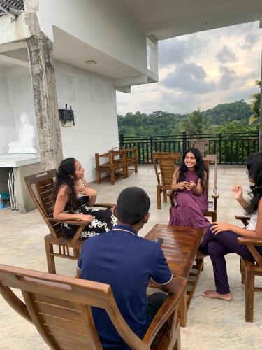 a group of people sitting on wooden chairs at Galkaduwa360 Villa in Kandy