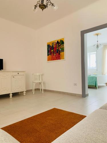 a white living room with a mirror and a chair at Dimora Paesana in Alberobello