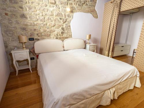 a bedroom with a white bed and a stone wall at Numero 6 in Todi