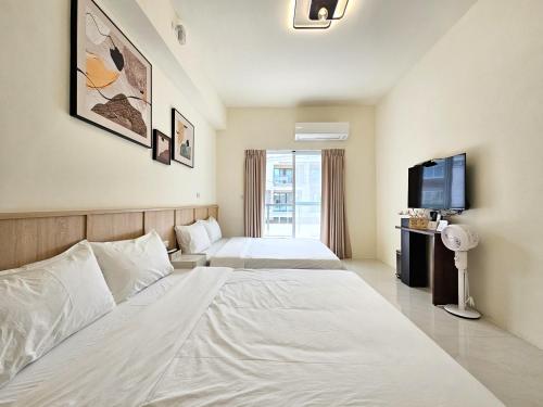a hotel room with two beds and a tv at Jung House in Taitung City