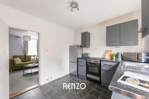 a kitchen with stainless steel appliances and a living room at Gorgeous 2-bed Home in Newark on-Trent by Renzo, Free Parking, Brilliant Location! in Newark upon Trent