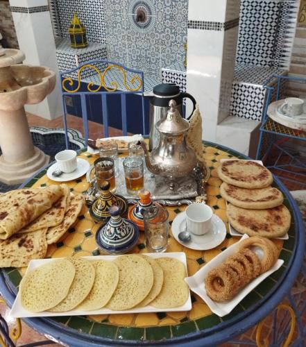 a table with a tray of bread and pastries on it at appartement dans une maison Safiote de charme in Safi