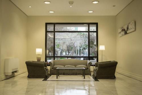 a living room with a couch and two chairs and a window at Austral Plaza Hotel in Comodoro Rivadavia