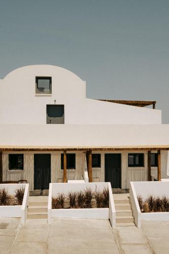 a white building with white benches in front of it at Gazelle Living in Imerovigli