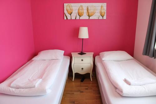 two beds in a room with a pink wall at Green House Apartments in Grundarfjordur