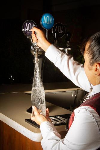 a woman is holding a bottle on a counter at Austral Plaza Hotel in Comodoro Rivadavia