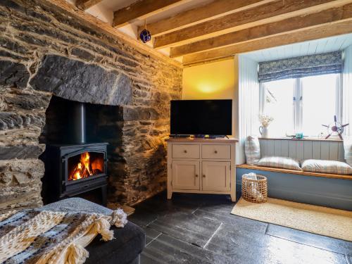 a living room with a stone fireplace and a television at Pengarreg in Barmouth