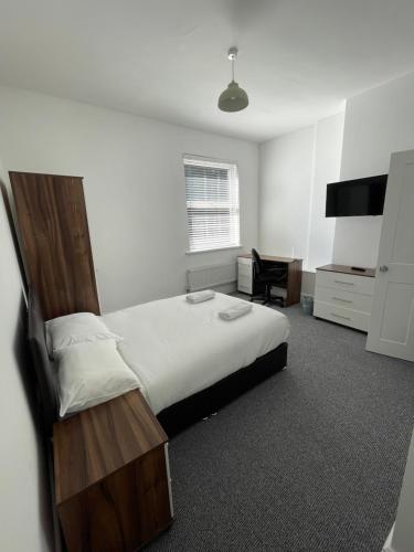 a bedroom with a large bed and a desk at ISUITES in Newcastle under Lyme