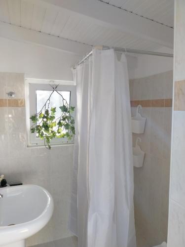 a bathroom with a sink and a white shower curtain at Olive garden room in Kánalos