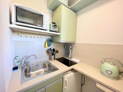 une petite cuisine avec un évier et un micro-ondes dans l'établissement PGH N35 - à 50m de la Plage avec Parking Privé, à La Grande Motte
