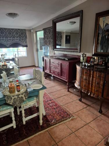a living room with a table and a mirror at Big Tree Guesthouse Brits in Brits