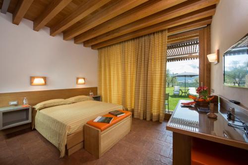 ein Schlafzimmer mit Bett, Schreibtisch und Fenster in der Unterkunft Pecora Vecchia - ColleMassari Hospitality in Cinigiano