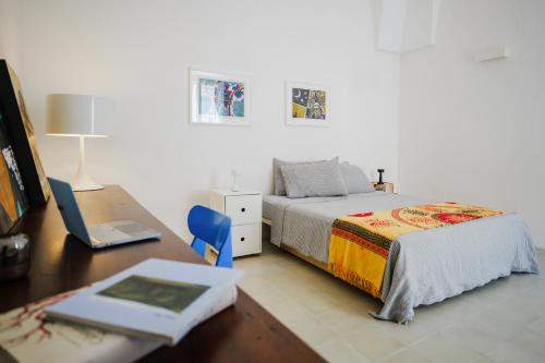 a bedroom with a bed and a desk with a laptop at PugliaEclectic - A Modern Oasis in the Heart of Puglia in San Vito dei Normanni
