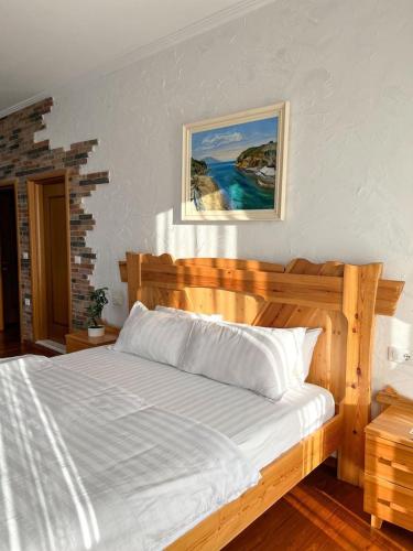 a bedroom with a wooden bed and a painting on the wall at Nurellari Winery Cellar and Guest House in Berat