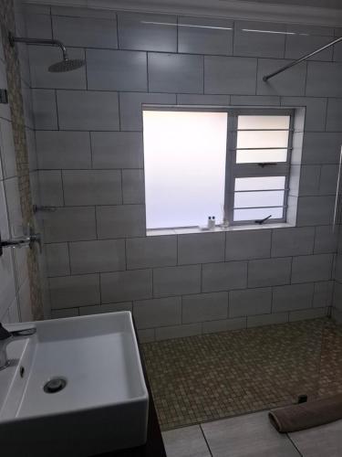 a bathroom with a white sink and a window at Big Tree Guesthouse Brits in Brits
