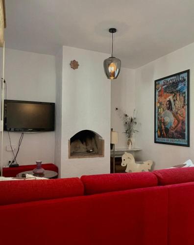a living room with a red couch and a fireplace at casa entre mer et montagne in Arcos de la Frontera