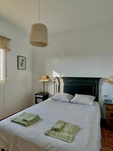 a bedroom with a bed with two green towels on it at casa entre mer et montagne in Arcos de la Frontera